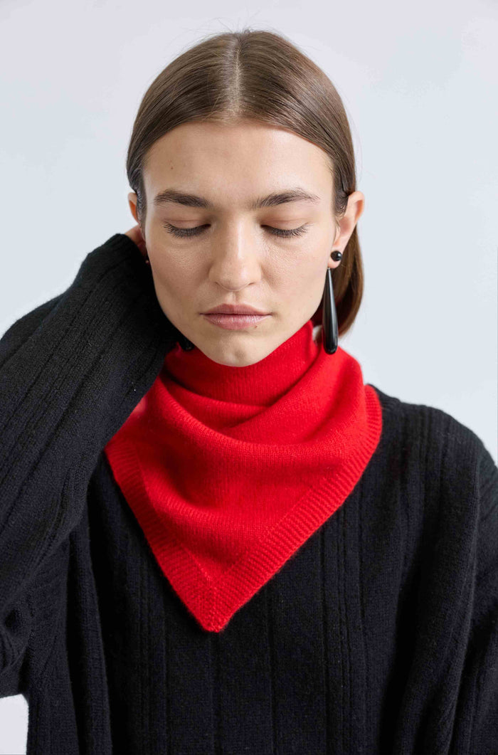 Woman wearing a black sweater and red scarf against a light gray background